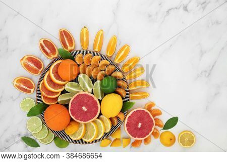 Citrus fruit high in antioxidants & vitamin c, with oranges, lemons, limes , mandarins & grapefruit on plates. Also high in anthocyanins, lycopene and dietary fibre. Health care concept. On marble.  