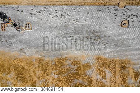 Worker With Vibratory Plate Compactor Compacting Sand At Road Or Sidewalk Construction Site