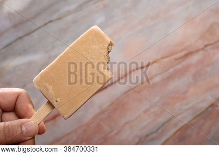 Hand Holding A Fresh Tapioca Milk Tea Flavor Popsicle With A Bite