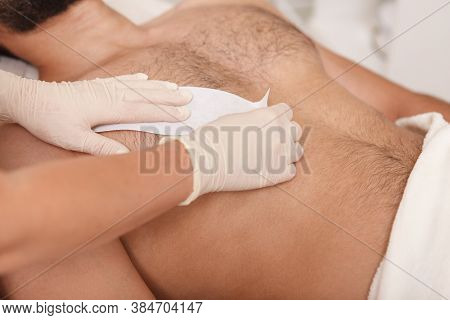 Cosmetologist Doing Waxing On Torso Of Unrecognizable Male Client