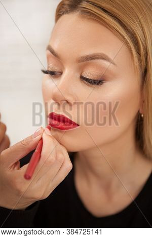 Vertical Portrait Of A Gorgeous Woman Having Her Lips Painted Red By Makeup Artist