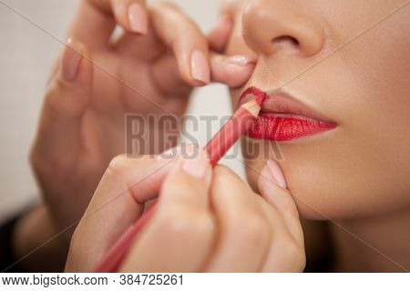 Cropped Close Up Of A Makeup Artist Using Red Lip Pencil On Her Female Client