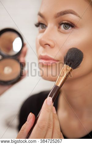 Cropped Vertical Closeup Of Makeup Artist Applying Highlighter On Cheekbones Of A Gorgeous Female