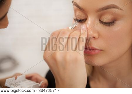 Makeup Artist Sticking False Lashes On Eyelids Of A Female Client