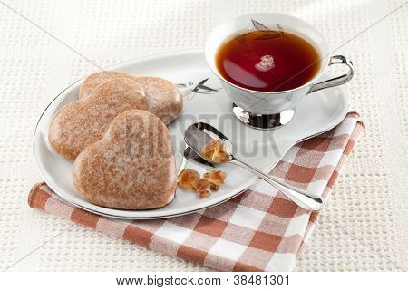 Cookies hjerte, brun farin, skeen, sort te, underkop på dug