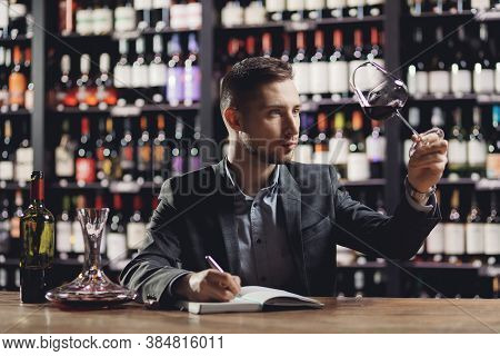 Man Sommelier Is Holding Glass Of Wine And Tasting Transparency Light Sediments In Restaurant