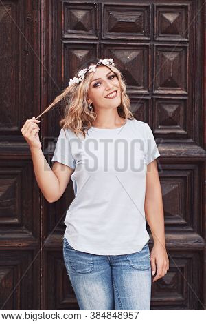 Young Women Wearing T-shirt And Jeans Stays Near A Wooden Door