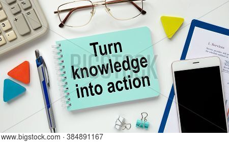Desktop With Documents, Calculator And Smartfon. Inscription Turn Knowledge Into Action On Notepad