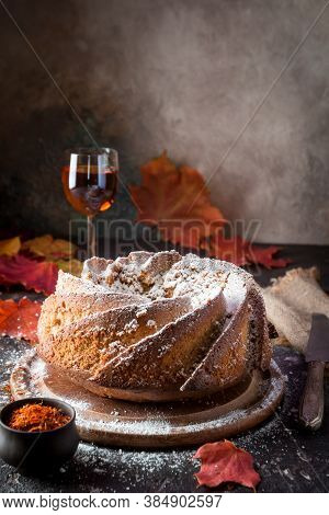 Bundt Cake With Saffron And Rum Covered With White Glaze On Rustic Background With Autumn Decoration