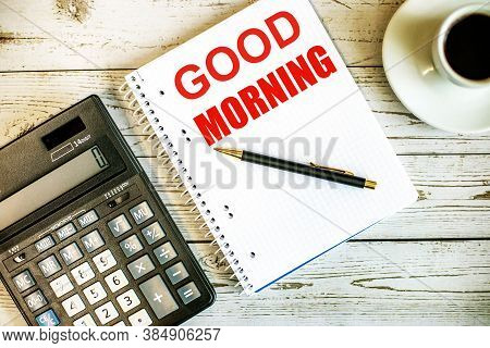 Good Morning Is Written In Red On A Light Wooden Onet Next To A Coffee Cup And A Calculator. Motivat