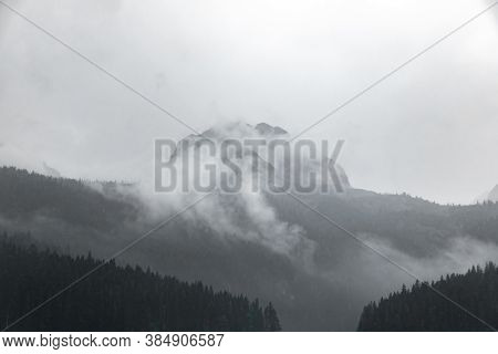 Black And White Photo Of A High Rocky Mountain In The Clouds