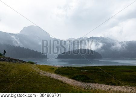 Black Deep Lake Of Glacial Origin Against The Background Of The High Rocky Mountain Zabljak, Montene