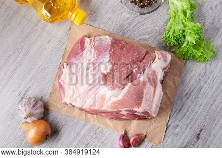 A Piece Of Uncooked Meat Of Pork Neck On Black Stome Plate With Ingredient On Gray Table. Ready To B