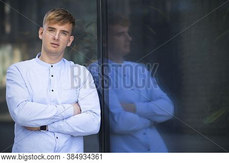 Portrait Of Handsome Serious Man, Young Blonde European Guy Looking At Camera In White Shirt With Ha