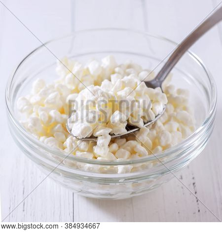 Food And Dairy Products Concept - Close Up Of Homemade Cottage Cheese In Glass Bowl On Wooden Table