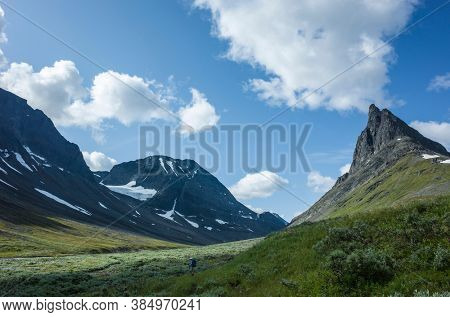 Hiking in picturesque Swedish Lapland landscape. Nallo mountain in northern Sweden. Arctic environment of Scandinavia in summer sunny day with big fluffy clouds