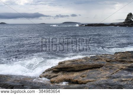 The Rocky Coast Of Maine Under A Stormy Dramatic Sky In Bristol Maine.