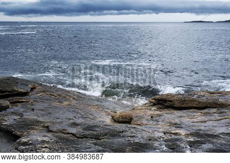 The Rocky Coast Of Maine Under A Stormy Dramatic Sky In Bristol Maine.