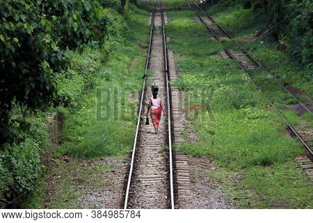 Behind Of Myanmarese Lady Villager Walking On The Railroad Tracks And Put The Black Bag Or Belonging