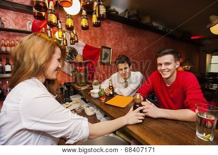 Female bartender serving beer to men at bar counter