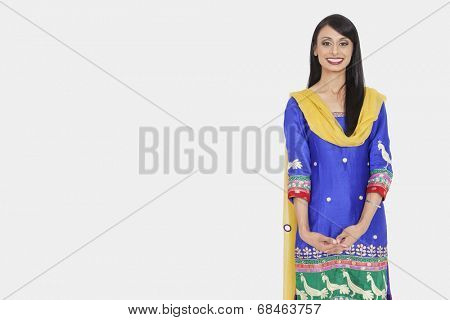 Portrait of an attractive Indian female in traditional wear standing over gray background