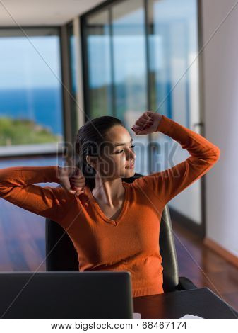 beautiful young woman relax and work on laptop computer while listening music on heaphones and read book at home