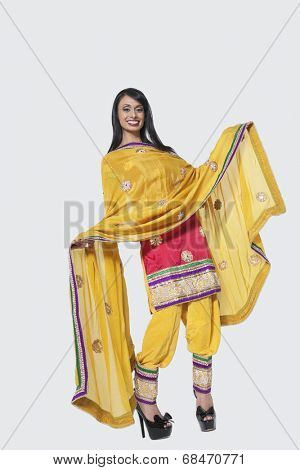Full length of an Indian woman in salwar kameez standing over gray background