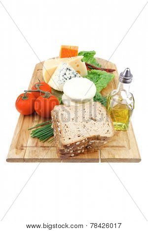 fresh aged french cheeses chops on big cutting board with tomatoes olive oil, rye breadm and green chives isolated over white background