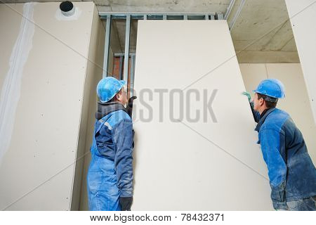 cheerful plasterboard workers team at a indoors wall insulation works