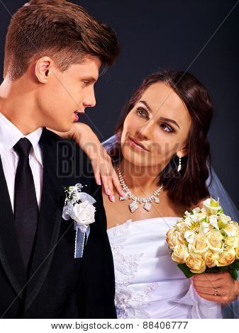 Bride and groom wearing wedding dress and costume fn black background.