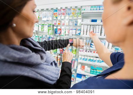 Mid adult female customer showing smartwatch to pharmacist in drugstore