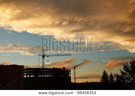 Industrial Tower Crane On A Construction Site And Building Silhouettes At Sunset Sky
