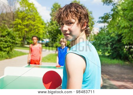 Boy with racket turned and playing table tennis