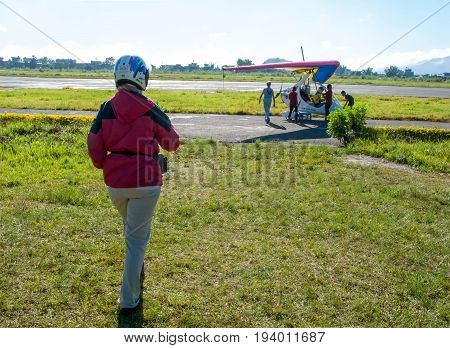 HIMALAYAS, POKHARA, NEPAL. 28 September 2008: Foreign tourist prepares for flight on a hang glider (deltaplan).