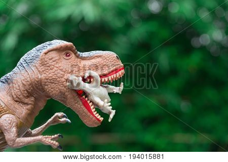 gigantic tyrannosaurus catches a smaller dinosaur in front of trees