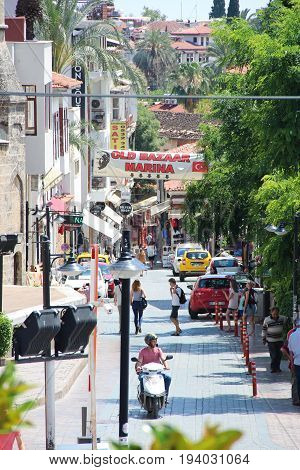 Antalya, Turkey - May 29 2017: Street view in old town - Kaleici, with pedestrians, tourists, cars and motorcyclists, vertical photo.