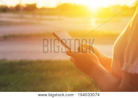 Using mobile phone on the street in morning woman typing message on smartphone during sunrise