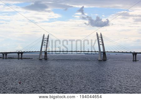 View of the cable-stayed bridge across the Strait on the background of sea and blue sky, summer evening