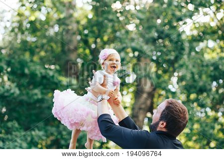 Young father playing with his daughter by lifting it up. Happy father and daughter
