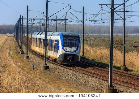 Flevoland the Netherlands - March 26 2016: Dutch snel train traveling through countryside.
