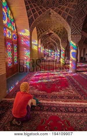 SHIRAZ IRAN - OCTOBER 23 2016 : Unidentified woman traveler see the colorful light through stained glass window inside Nasir Al-Mulk (Pink Mosque) a traditional mosque in Shiraz Iran.