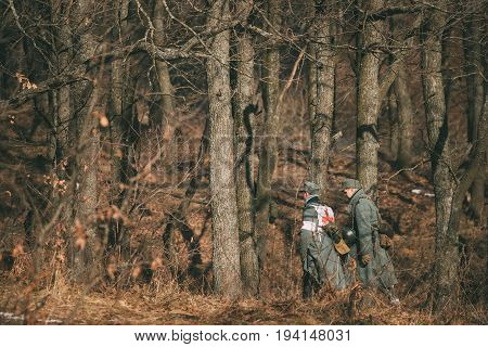 Rogachev, Belarus - February 25, 2017: Two Unidentified Re-enactors Dressed As German Wehrmacht Infantry Soldiers In World War II Marching Along Forest Road At Autumn Season.