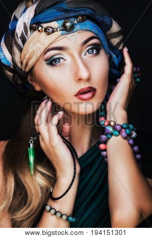 Portrait of young beautiful woman close up. Perfect makeup. Perfect skin. Fashion photo.Beauty lady with colored turban over blue background