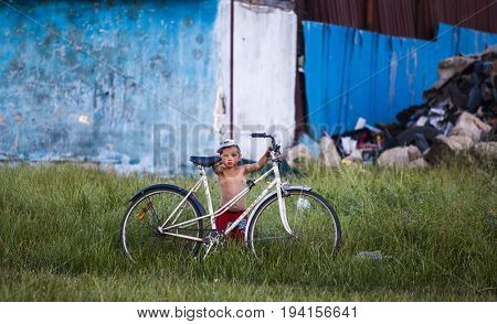 Cluj-Napoca, Romania - 27 June 2017: Unidentified child carrying a bicycle in the isolated poor romani community of Pata Rat, the rubbish dump near Cluj-Napoca, Romania