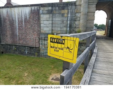 cement building with yellow caution watc your step sign