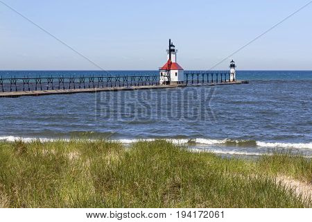 Photographed atop a dune two lighthouses mark the mouth of the Michigan's St. Joseph River as waves gently break on a sandy Lake Michigan beach.