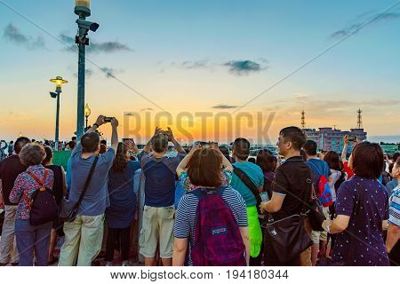 TAIPEI TAIWAN - MAY 29: Tourists taking photos of the sunset from a pier in the Fisherman's Wharf area of Tamsui on May 29 2017 in Taipei