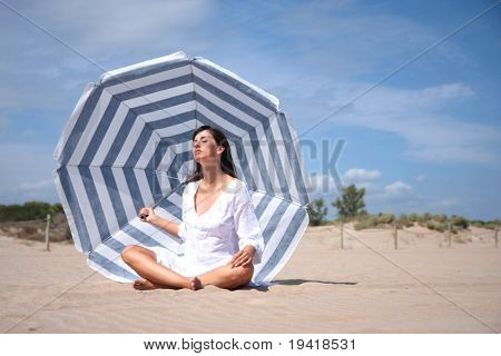 recreatin 在海岸上的蓝白色条纹阳伞下的女人