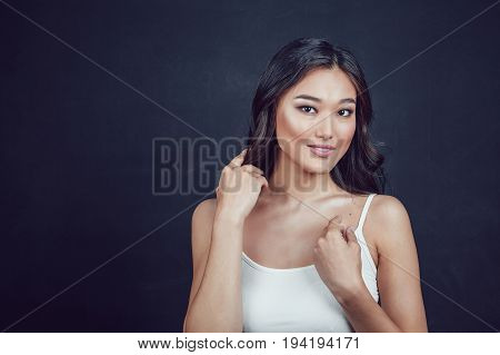 Portrait of a beautiful asian woman with makeup and light curls on black background.