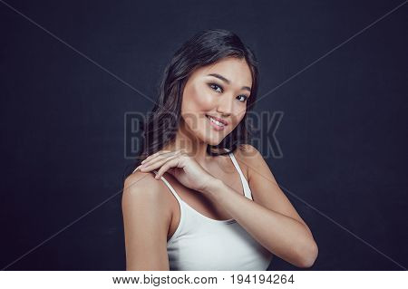Portrait of a beautiful asian woman with makeup and light curls on black background.